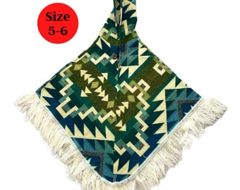 Könnte beinhalten: Ein Kapuzenponcho mit einem geometrischen Muster in Blautönen, Grün und Weiß. Der Poncho hat einen Fransenrand und ist mit "Größe 5-6" gekennzeichnet.