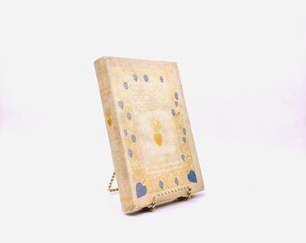 Könnte beinhalten: Ein Vintage-Buch mit einem goldenen und weißen Einband. Der Einband zeigt ein Herzdesign mit einer Krone und den Text "Illustrata per Giovanni Boccaccio".