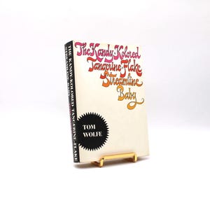 May include: A book titled "The Kandy-Kolored Tangerine-Flake Streamline Baby" by Tom Wolfe. The title is written in a colourful, stylised font.