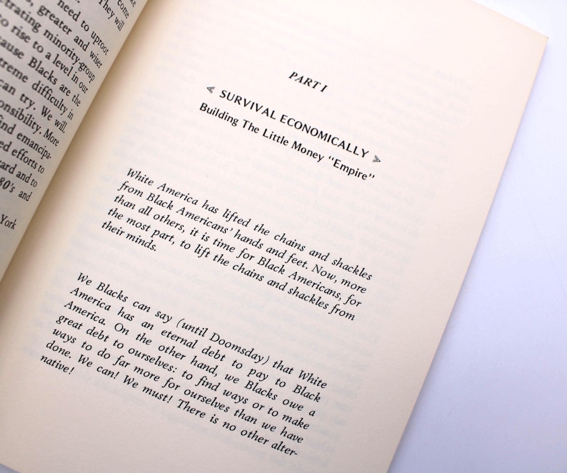 May include: An open book with text on the page. The text reads "PART I SURVIVAL ECONOMICALLY Building The Little Money Empire". The text discusses Black Americans and White America. The book is on a white surface.