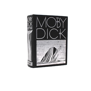 May include: A hardcover book titled Moby Dick, illustrated by Rockwell Kent. The black cover features silver text and a graphic illustration of a whale breaching the water. The spine displays the title, author, and a whale tail illustration.