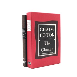 May include: A red slipcase featuring a black rectangular frame with the text Chaim Potok The Chosen 25th Anniversary Edition, containing a dark brown hardcover book with the same title and author printed in white on the spine.