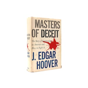 Könnte beinhalten: Ein Vintage-Buch mit dem Titel "Masters of Deceit" von J. Edgar Hoover. Der Einband des Buches ist cremefarben mit schwarzem und blauem Text und einem roten Spritzmuster. Titel und Autor des Buches sind deutlich sichtbar.