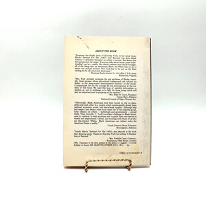 May include: A book titled "Survival For The 1990's And Beyond" by Dorothy York, with text on the back cover. The book is propped up on a gold-coloured stand. The cover features text and quotes.