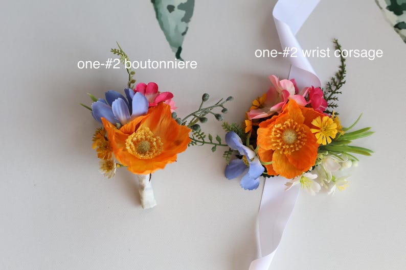 May include: A boutonniere and a wrist corsage labeled one-#2, featuring artificial orange poppies, blue flowers, small yellow blossoms, and green foliage. The wrist corsage includes a white satin ribbon for attachment to the wrist.