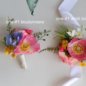 May include: A boutonniere and a wrist corsage featuring artificial pink poppies, blue flowers, yellow blossoms, and green foliage. The boutonniere has a white wrapped stem, and the wrist corsage includes a white ribbon. Text reads one-#1 boutonniere and one-#1 wrist corsage.