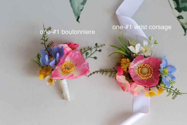 May include: A boutonniere and a wrist corsage featuring artificial pink poppies, blue flowers, yellow blossoms, and green foliage. The boutonniere has a white wrapped stem, and the wrist corsage includes a white ribbon. Text reads one-#1 boutonniere and one-#1 wrist corsage.