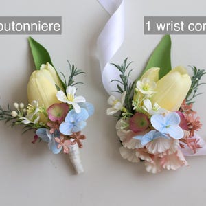 Op de afbeelding: Een corsage en een polscorsage met gele tulpen, witte en blauwe bloemen en groen. De corsage is omwikkeld met een wit lint. De tekst in de afbeelding luidt: "1 corsage" en "1 polscorsage."