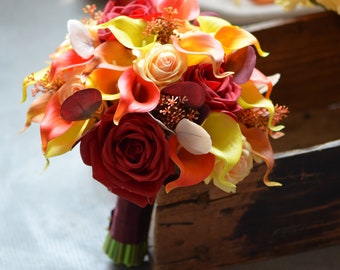 May include: A bridal bouquet with red, orange, and yellow flowers. The bouquet includes roses, calla lilies, and other assorted flowers.