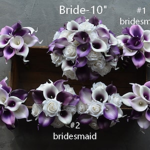 May include: A set of six bridal bouquets featuring white and purple calla lilies and white roses. The bouquets are arranged in a wooden box. The bride's bouquet is labeled "Bride-10" and the bridesmaid bouquets are labeled "#1 bridesmaid" and "#2 bridesmaid".