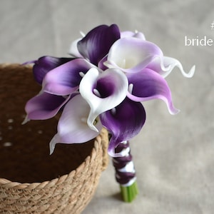 May include: A bouquet of purple and white calla lilies, tied with a purple ribbon. The bouquet is labeled "#1 bridesmaid".