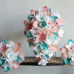 May include: A set of three cascading bouquets featuring peach, white, and teal flowers. The bouquets are made with silk flowers and include starfish accents.