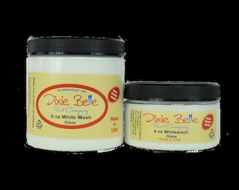 May include: Two jars of Dixie Belle Paint Company White Wash Glaze. The smaller jar is 4 ounces and the larger jar is 8 ounces. Both jars are white with black lids and a yellow label with the Dixie Belle logo and text. The jars are on a white background.