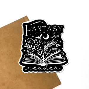 May include: Black and white sticker with an open book, vines, a crescent moon, a bat, and the text "Fantasy reader".