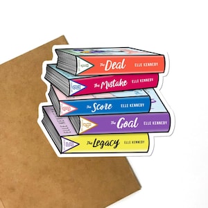 May include: A sticker featuring a stack of five books with colorful spines. The titles are "The Deal", "The Mistake", "The Score", "The Goal", and "The Legacy" by Elle Kennedy. The sticker is on a brown surface.