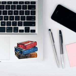 Peut inclure: Une pile de quatre livres broch&eacute;s avec des couvertures bleues, rouges et blanches. Les livres sont intitul&eacute;s "Crescent City" par Sarah J. Maas.
