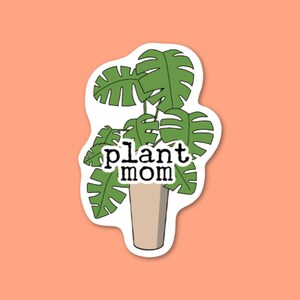 Puede incluir: Una planta verde con hojas grandes en una maceta marr&oacute;n con el texto "plant mom" en ella.
