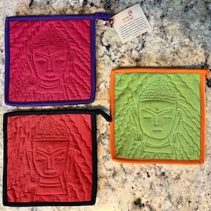 May include: Three quilted pot holders with a Buddha image in the center. The pot holders are red, green, and orange with purple, black, and orange trim.
