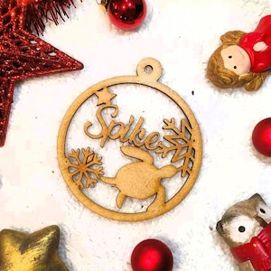 May include: A wooden Christmas ornament with a cutout of a turtle and snowflakes. The ornament is personalized with the name "Spike".
