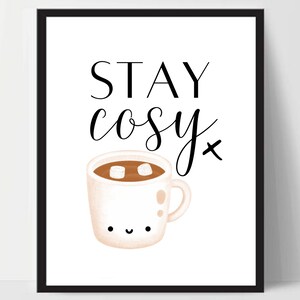 Puede incluir: Una impresi&oacute;n de arte imprimible blanca con texto negro que dice "STAY cosy" y una ilustraci&oacute;n de dibujos animados de una taza blanca con un l&iacute;quido marr&oacute;n y malvaviscos blancos en su interior. La taza tiene una cara feliz.
