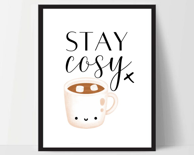 Puede incluir: Una impresi&oacute;n de arte imprimible blanca con texto negro que dice "STAY cosy" y una ilustraci&oacute;n de dibujos animados de una taza blanca con un l&iacute;quido marr&oacute;n y malvaviscos blancos en su interior. La taza tiene una cara feliz.