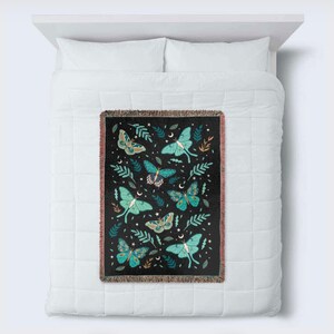 May include: A black woven throw blanket with a pattern of green and blue moths and leaves on a black background.