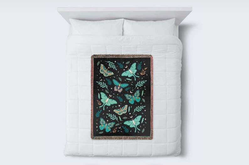 May include: A black woven throw blanket with a pattern of green and blue moths and leaves on a black background.