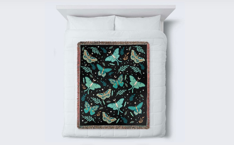May include: A woven throw blanket with a black background and a repeating pattern of green and blue moths, leaves, and stars.