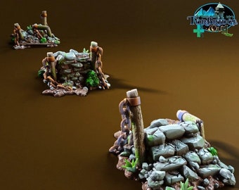 Könnte beinhalten: Drei Miniaturbauten aus Stein und Holz mit Ketten und grünem Laub. Die Strukturen sind Teil eines Brettspiels namens "Torbridge Cult".