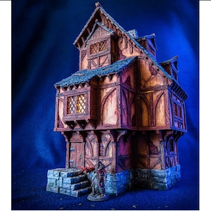 Puede incluir: Un modelo en miniatura detallado de un edificio de tres pisos con estructura de madera y cimientos de piedra. El edificio tiene un techo de inclinaci&oacute;n pronunciada, varias ventanas y una peque&ntilde;a puerta. El modelo est&aacute; pintado en tonos de marr&oacute;n, gris y blanco, y se coloca sobre un fondo azul.