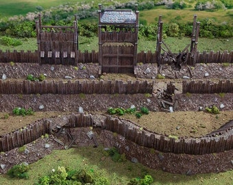 May include: A miniature wooden fort with a gate and a tower. The fort is surrounded by a wooden fence and a moat. The fort is partially destroyed, with some of the walls and the gate broken. The fort is set on a grassy field.
