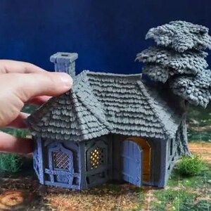 Puede incluir: Una caba&ntilde;a en miniatura gris con techo de paja, una peque&ntilde;a puerta y ventanas. Un &aacute;rbol en miniatura gris est&aacute; al lado de la caba&ntilde;a.