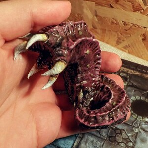 May include: A hand-painted, detailed miniature of a pink and brown creature with white claws. The creature has a textured, segmented body and appears to be a mythical beast.