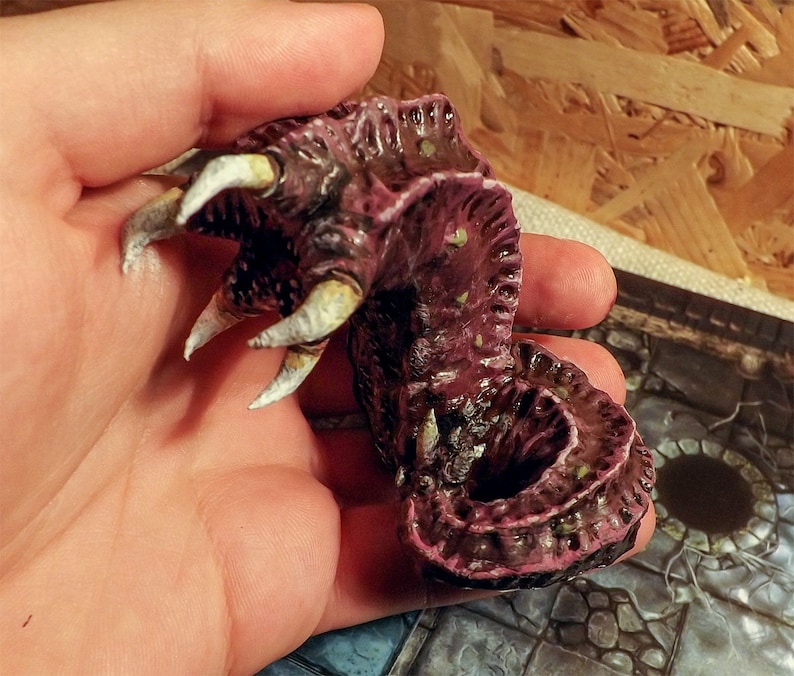 May include: A hand-painted, detailed miniature of a pink and brown creature with white claws. The creature has a textured, segmented body and appears to be a mythical beast.