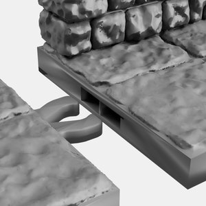 May include: Close-up of two gray stone wall sections with a connecting piece. The connecting piece has two slots and a gray plastic connector with two loops.