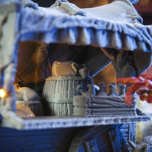 May include: A miniature wooden wagon with a canvas awning, a barrel, and other supplies. The wagon is painted in a light grey colour and has a wooden wheel.