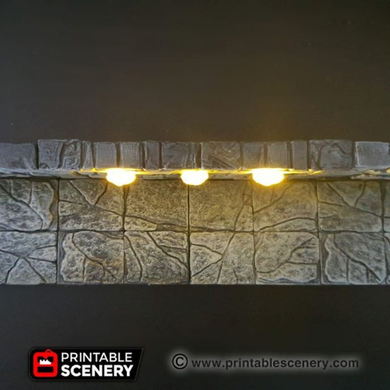 May include: A close-up of a stone wall with three small, round, white lights illuminating the wall. The wall is made of rough, textured stone and has a cracked, uneven surface. The lights are evenly spaced and cast a warm, inviting glow.