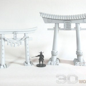 May include: Two white painted miniature Japanese Torii gates. The larger gate is taller and wider than the smaller gate. Both gates have a traditional design with a curved top and two vertical pillars.