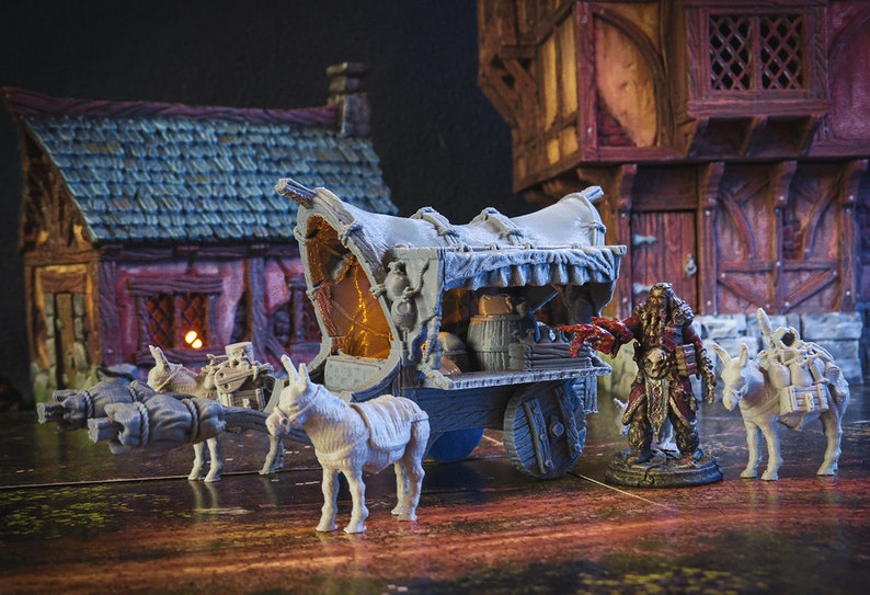 May include: A miniature model of a wagon pulled by two donkeys. The wagon has a canvas top and is loaded with barrels and other supplies. A miniature figure of a bearded man in a red and brown outfit stands next to the wagon.