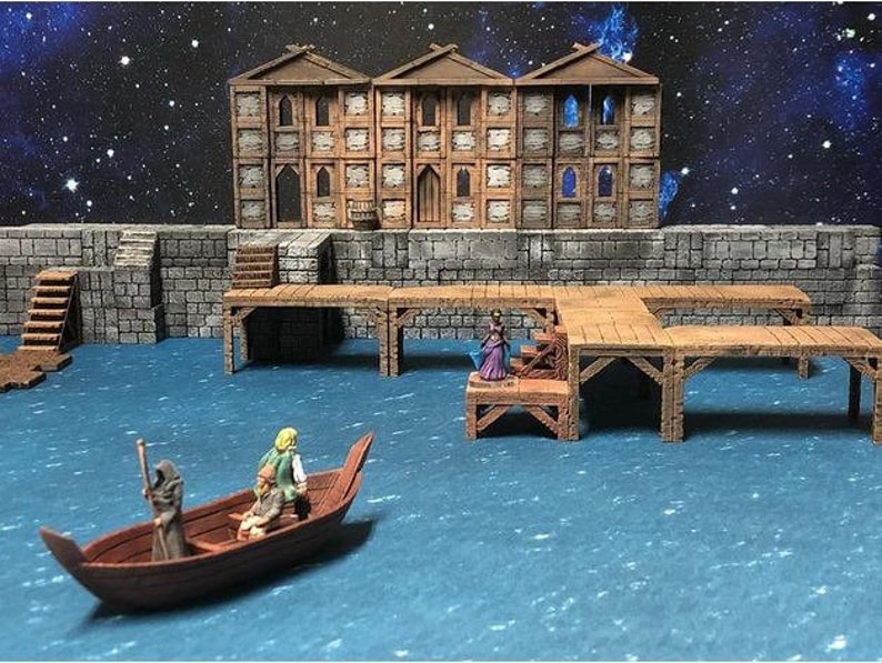May include: A miniature wooden dock with a building in the background. The dock has multiple levels and is made of brown wood. There are three figures on the dock, one of which is a woman in a purple dress. The dock is over a blue body of water.