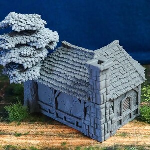 Puede incluir: Una caba&ntilde;a de piedra gris en miniatura con un techo de paja y un peque&ntilde;o &aacute;rbol a su lado. La caba&ntilde;a tiene una ventana con un dise&ntilde;o de celos&iacute;a y una chimenea. El modelo est&aacute; hecho de un material texturizado y est&aacute; dise&ntilde;ado para juegos de mesa o exhibici&oacute;n en miniatura.