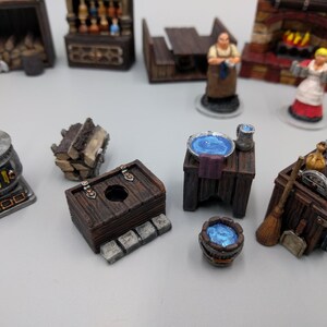 May include: A collection of miniature wooden furniture pieces, including a table with a blue bowl, a small wooden chest, a wood-burning stove, and a wooden cart with a broom and other items. The pieces are painted in brown, grey, and blue tones.