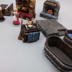 May include: A miniature wooden bar trolley with a blue cloth draped over the side. The trolley is filled with miniature bottles, glasses, and a broom. The trolley is on a white surface.