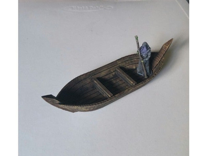 May include: A small wooden boat with a single figure standing in the middle. The figure is wearing a dark hooded robe and holding a staff. The boat has a pointed bow and a flat bottom.