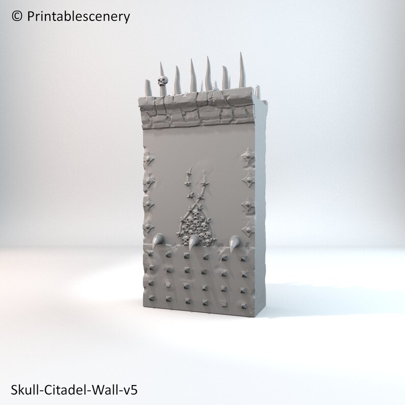 May include: A gray 3D printed model of a wall with a skull on top and spikes. The wall is decorated with skulls and spikes. The model is labeled "Skull-Citadel-Wall-v5".