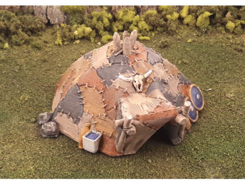 Puede incluir: Un modelo en miniatura de una caba&ntilde;a r&uacute;stica remendada con una puerta de madera y una decoraci&oacute;n de calavera. La caba&ntilde;a est&aacute; hecha de materiales marrones, grises y blancos y tiene un barril azul y blanco en el lateral.