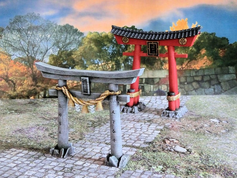 May include: Two traditional Japanese Torii gates, one red and one gray, with a rope and tassels hanging from the gray gate. The gates are set against a backdrop of trees and a stone wall.