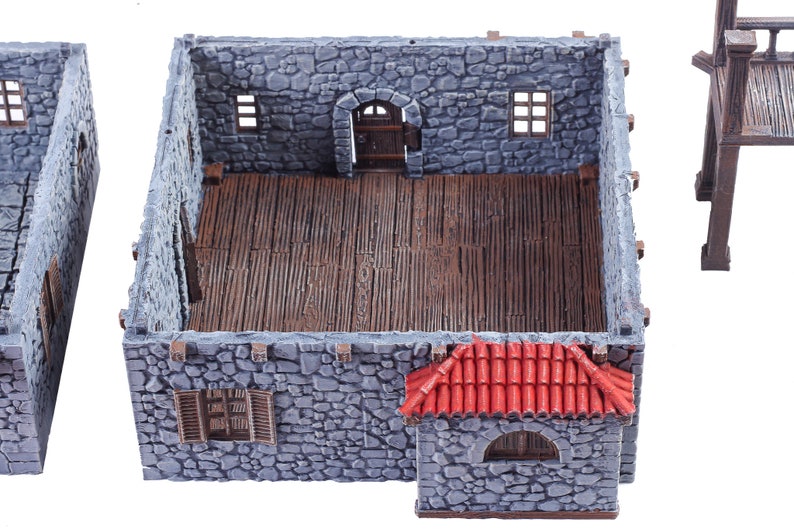 May include: A miniature stone building with a red tiled roof, a wooden door, and windows. The interior is visible and has a wooden floor.