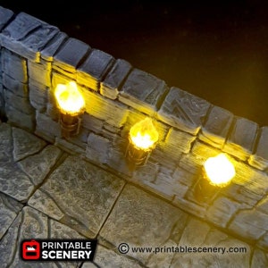 May include: Three small, yellow, flame-shaped lights are mounted on a stone wall. The lights are lit and casting a warm glow. The wall is made of rough, gray stone. The image is from the website www.printablescenery.com.