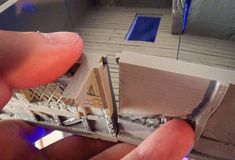 Puede incluir: Primer plano de dos piezas de un modelo impreso en 3D, mostrando una costura &aacute;spera y sin terminar donde las piezas se unen. El modelo es de color marr&oacute;n claro y tiene una superficie texturizada.